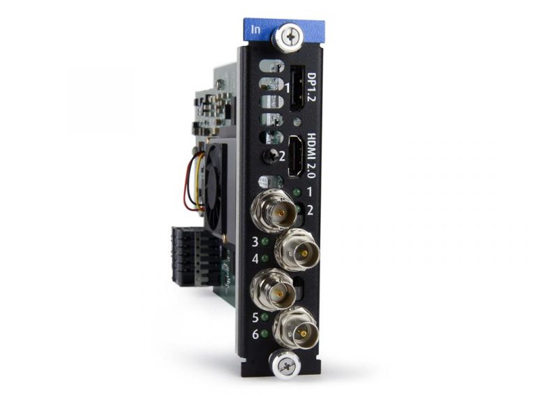 Nahaufnahme einer schwarzen elektronischen Platine mit beschrifteten Anschlüssen: DP1.2, HDMI 2.0 und sechs nummerierte Anschlüsse. An der Seite sind ein kleiner Lüfter und sichtbare Verkabelung zu sehen. Oben befindet sich eine blaue Lasche mit der Aufschrift „In“.